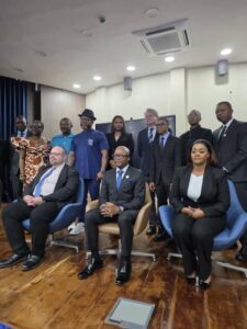 Group of professionals in formal attire posing for a photo in a conference room, with seated and standing members.