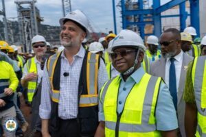 Group of diverse construction professionals wearing hard hats and high-visibility vests on a worksite, smiling as they tour the site.