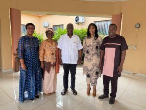| The Calabash Newspaper Five adults stand side by side indoors, smiling for a group photo in a light-colored lobby.