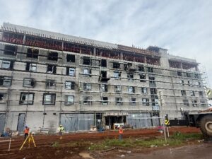 Multi-story concrete building under construction with scaffolding and workers on site.