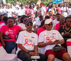 Crowd of people at a Breast Cancer Awareness event, many wearing pink and white shirts.