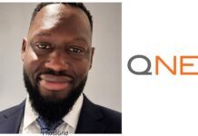 QNET Strengthens Anti-Scam Campaign as Sierra Leonean, Liberian Journalists Share Malaysia Experience Close-up of smiling man in a dark suit and white shirt, cropped at shoulders, against a neutral background (branding on right edge).